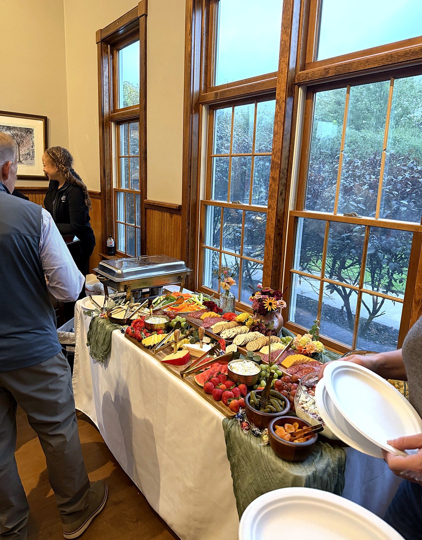 A long table of food beside tall windows