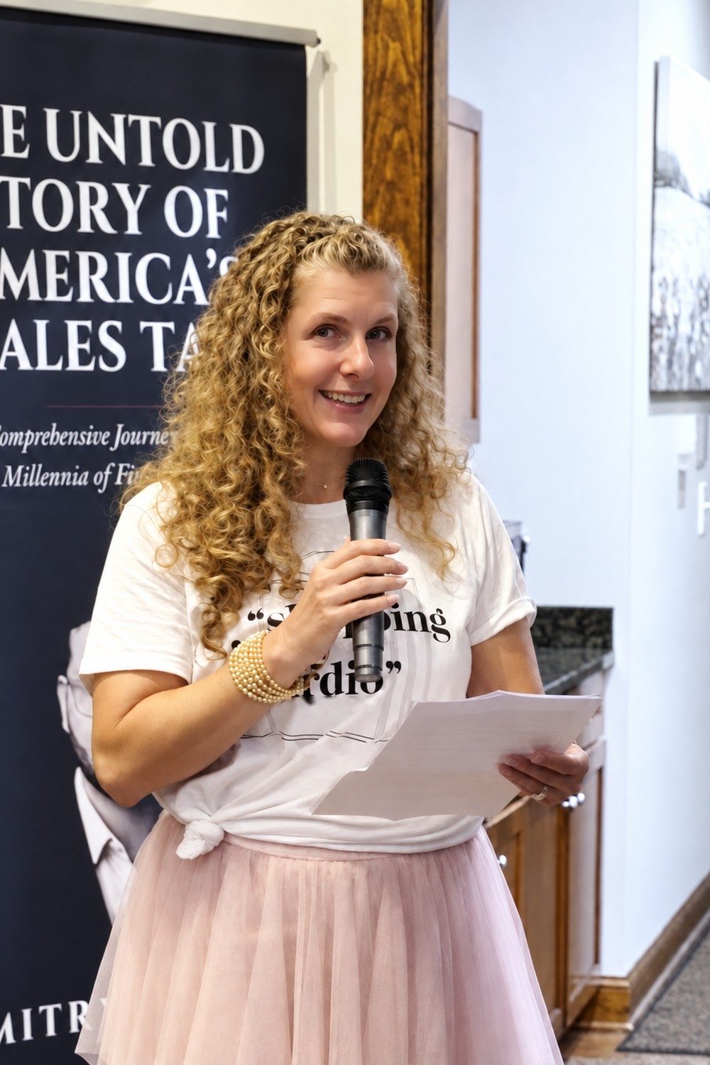 Sabrina Houser speaking in front of the book banner