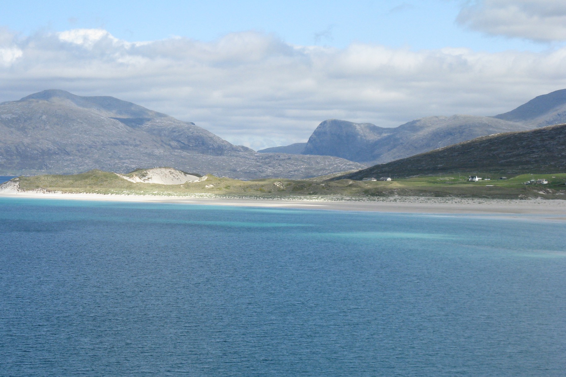 Turquoise water and a white sand beach at Luskentyre, with the grey hills of North Harris beyond