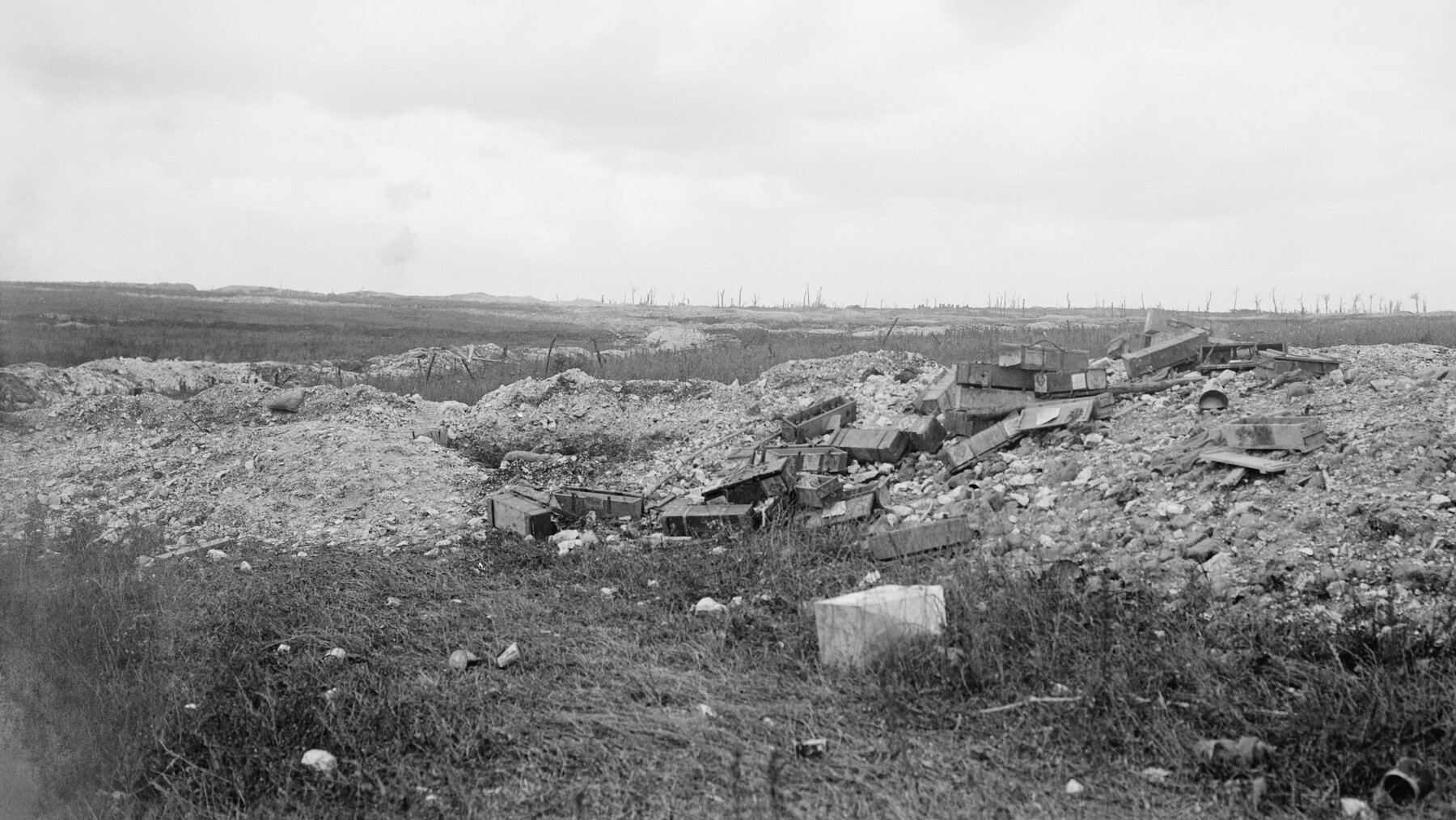 A ruined battlefield in black and white with a village on the horizon