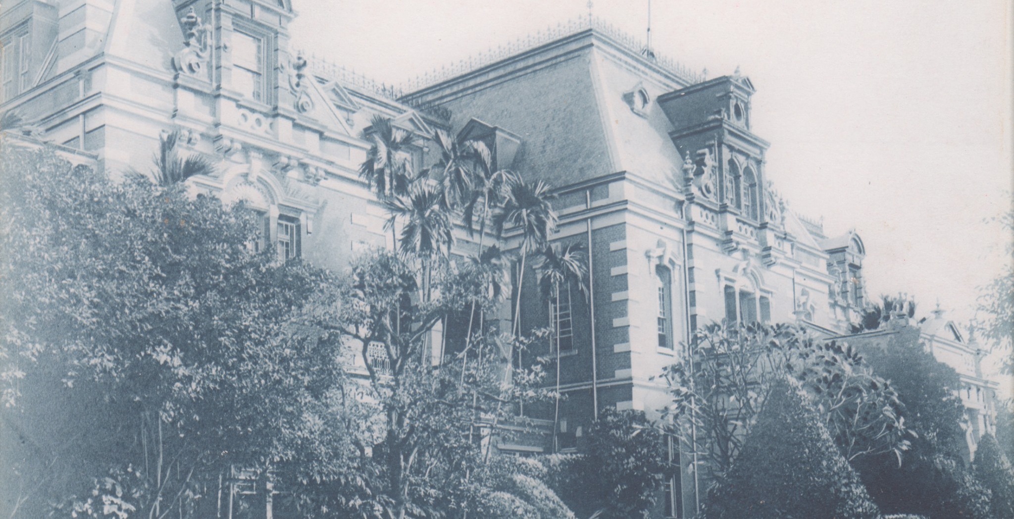 A 1930s postcard of the Taihoku Railway Hotel in Taipei, an ornate European-style building half hidden behind palms and trees