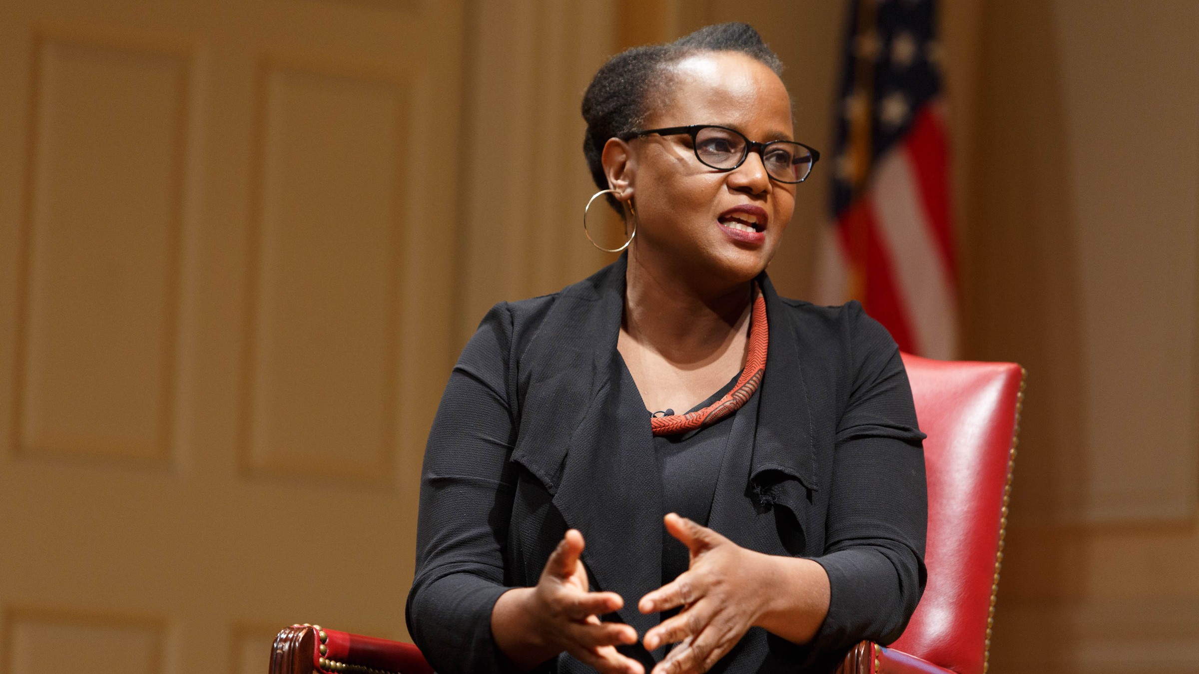 Edwidge Danticat, in glasses and a black jacket, speaking from a red leather chair on stage