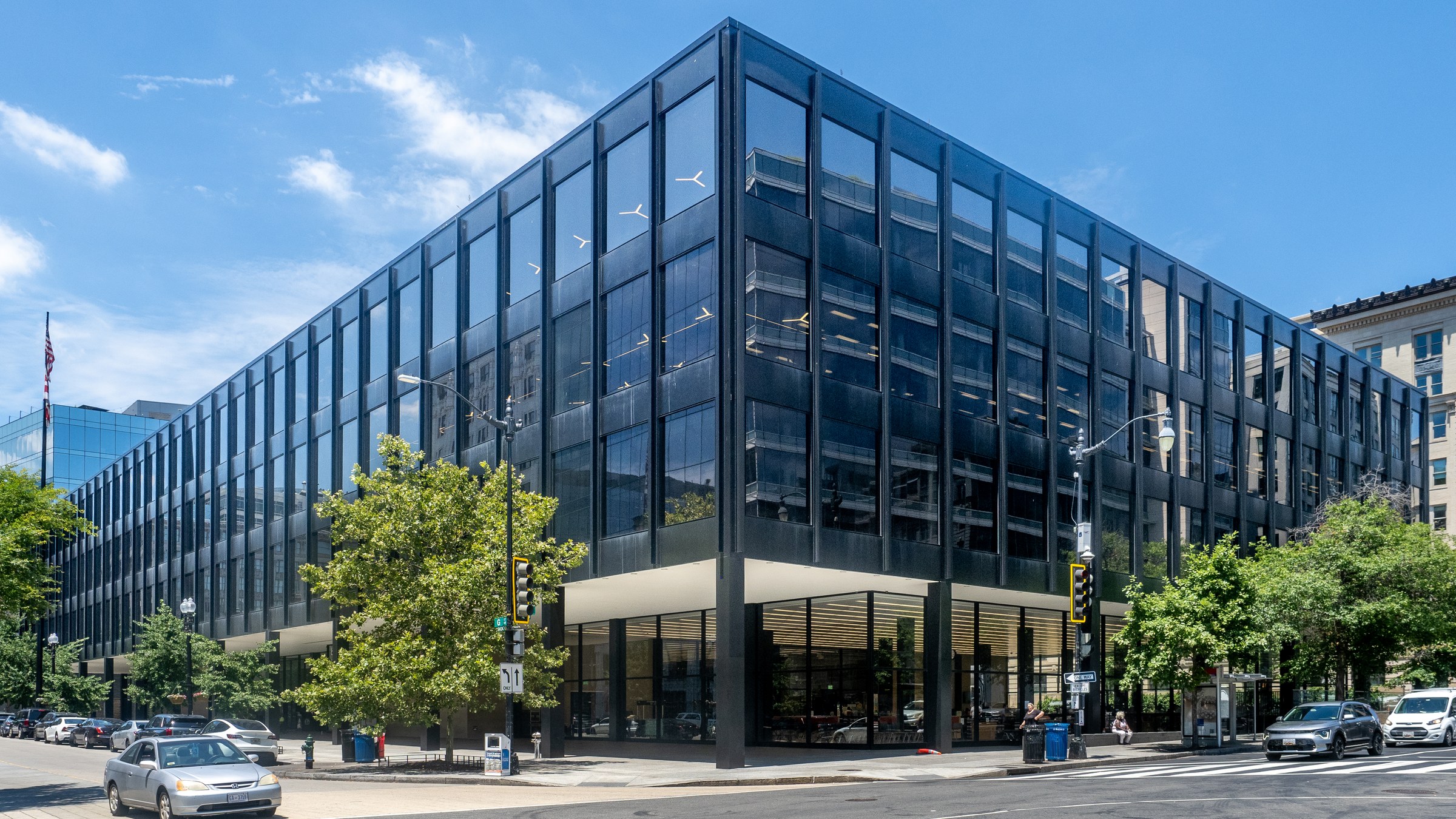 The black steel and glass Martin Luther King Jr. Memorial Library on a sunny street corner in Washington, with trees along the sidewalk
